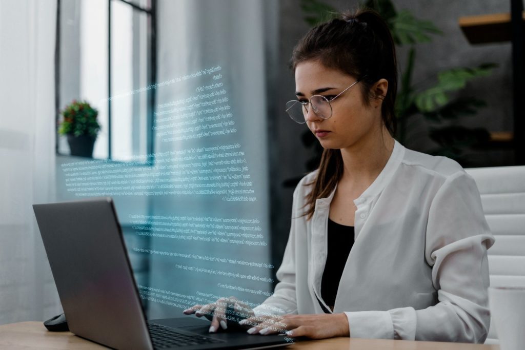 Mulher dentro de um escritório sentada em sua mesa trabalhando em seu notebook